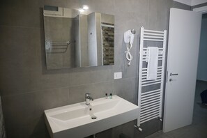 Ein Badezimmer mit einem weißen Waschbecken, einem Handtuchhalter und einem Spiegel.