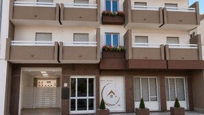Un edificio residencial de varios pisos con balcones, una entrada con portón y un letrero que dice 'IRINA ROOMS'.