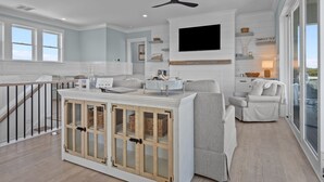 A spacious living area with a high ceiling, a mounted TV, and a built-in wooden cabinet. - Silver Lining- Luxury Retreat in Dolphin Ridge (Emerald Isle)