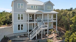 A two-story house with a balcony, a covered porch, and a staircase leading to the upper level. - Silver Lining- Luxury Retreat in Dolphin Ridge (Emerald Isle)