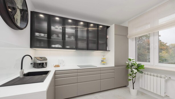 Eine moderne Küche mit Backofen, Spüle und Fenster mit Blick auf Bäume.