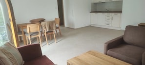 Un salon comprenant un canapé, une table basse en bois et un coin repas avec des chaises et une table.