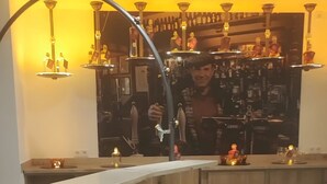 Zona de bar con taburetes, barra y un letrero iluminado de gran tamaño.