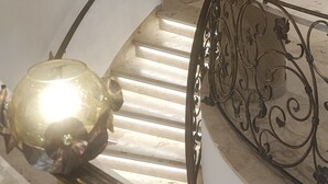 A marble staircase with a golden spherical object at the bottom, a handrail with floral patterns, and a light fixture above. - Apartment in A Hotel 'Einhorn' with Mountain View, Shared Terrace and Wi-Fi (Schwäbisch Gmünd)