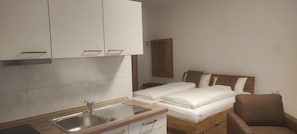 Una habitación pequeña y limpia con cama, una silla, un lavabo y armarios.