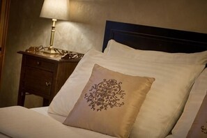 A neatly made bed with a decorative pillow, a bedside table with a lamp, and a dark headboard. - Angelis (Prague)