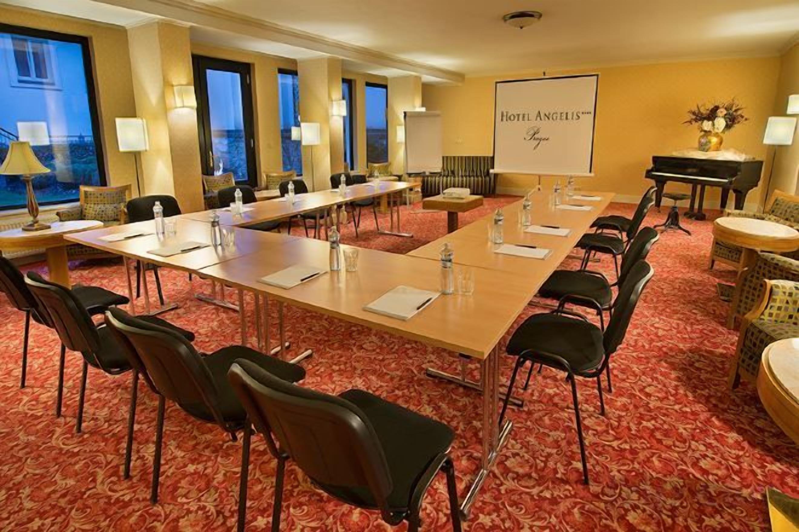 Une salle de conférence équipée d’une longue table, de chaises et d’un écran de projection.