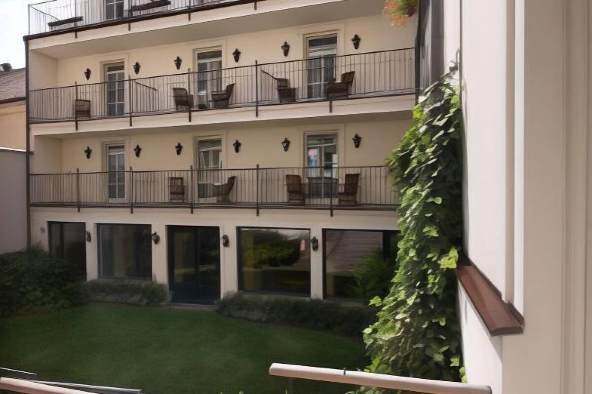 A multi-story building with balconies, windows, and a small garden area.