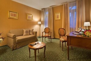 A hotel room with a sofa, two armchairs, a small table, a desk, and a lamp. - Angelis (Prague)
