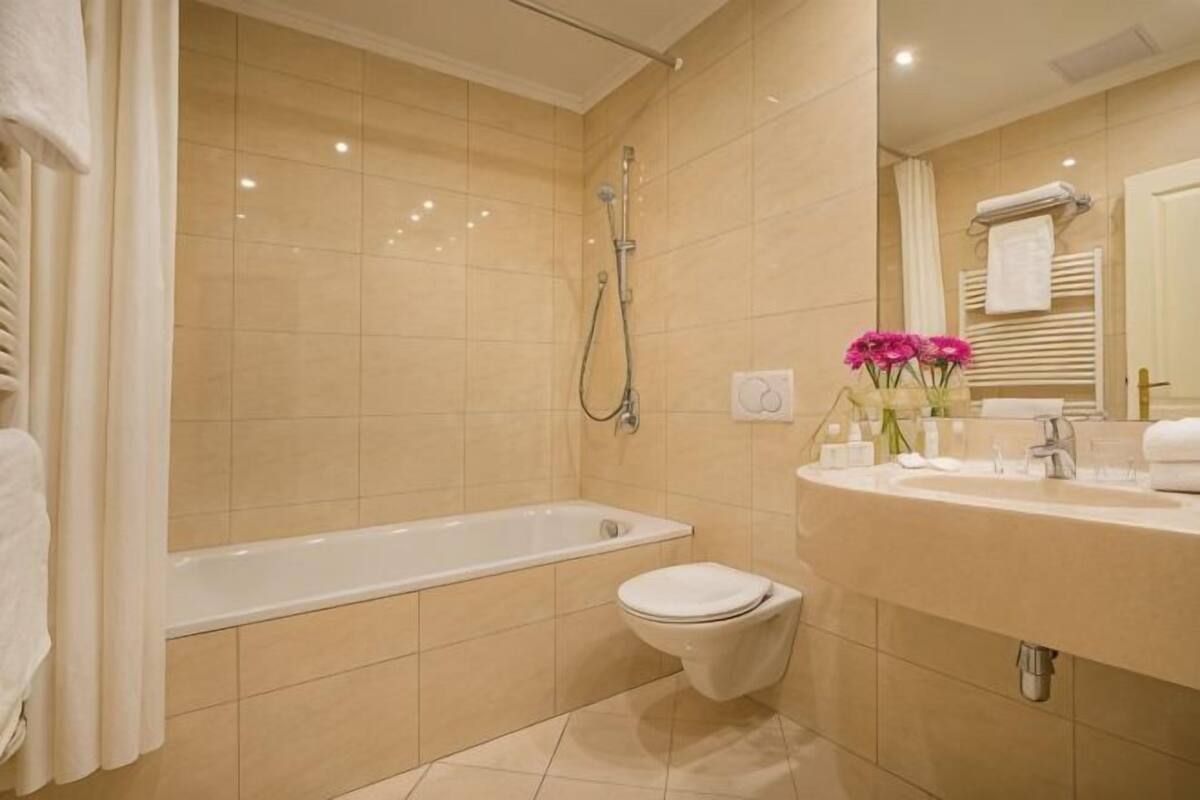 A bathroom with a bathtub, toilet, sink, and mirror.