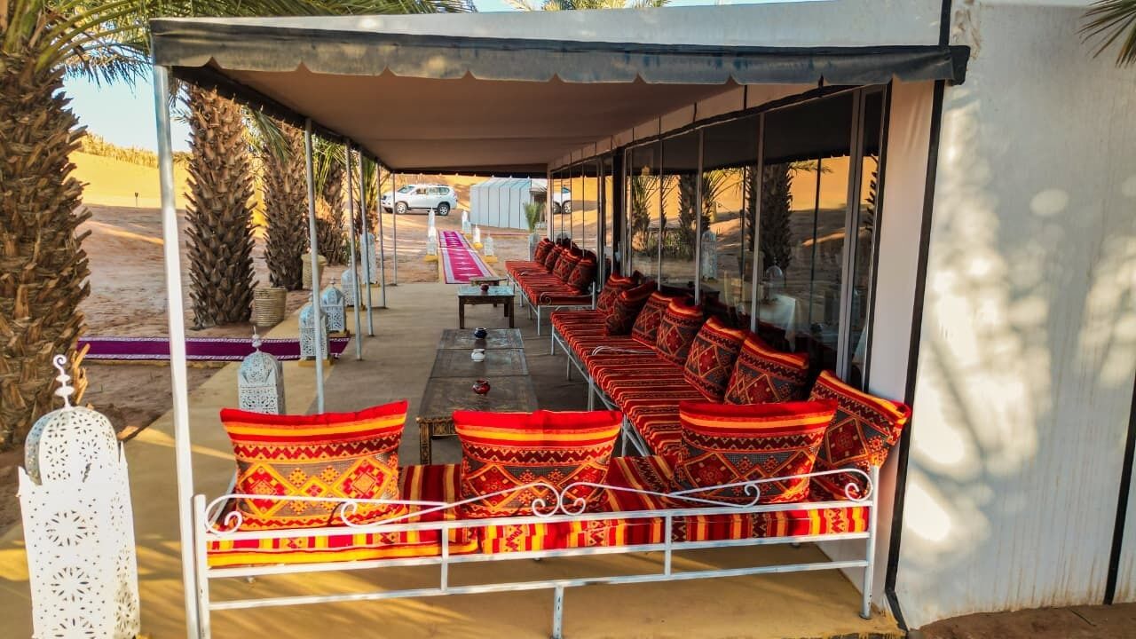 A covered outdoor seating area with patterned cushions and a metal railing.