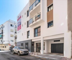 Un immeuble moderne à plusieurs étages, avec une voiture garée devant.