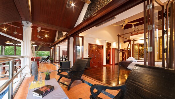 A spacious room with a wooden ceiling, a large bed, a seating area with chairs, and a view of the outdoors. - Lumaya Rawai (Rawai)