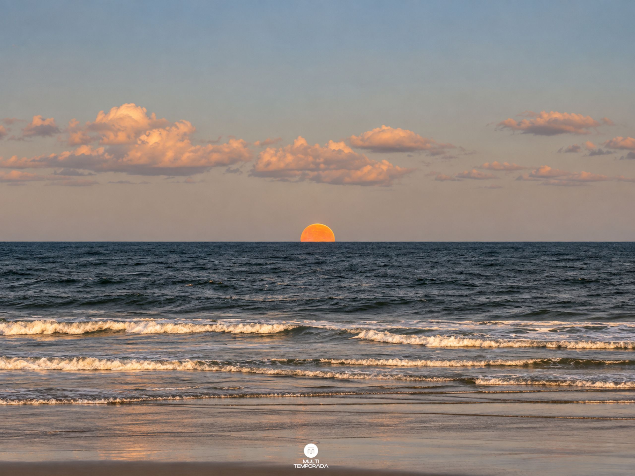 Una playa con olas y un atardecer.