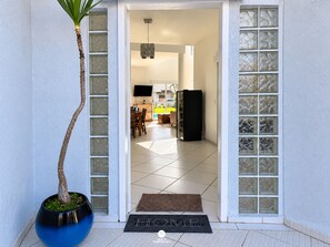 A doorway leading to a kitchen with a refrigerator and a dining area. - Casa de Praia Brisa do Oceano com Piscina Privativa - São Francisco do Sul (São Francisco do Sul)