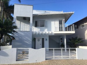 Ein zweistöckiges Haus mit Balkon, Eingangstür und einem kleinen Garten.