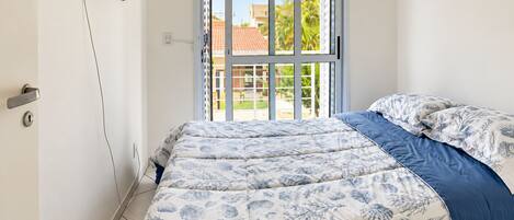 A bedroom with a bed, a television mounted on the wall, and a sliding glass door leading to an outdoor area.