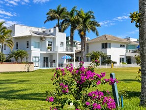 Un hôtel à plusieurs étages doté de balcons, de palmiers et d’une pelouse bien entretenue.