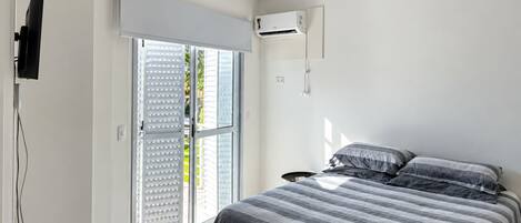 Un dormitorio con cama, ventilador de techo, equipo de aire acondicionado y puerta corrediza de vidrio.