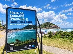 A sign with a beach scene and text in Portuguese. - Casa de Praia Brisa do Oceano com Piscina Privativa - São Francisco do Sul (São Francisco do Sul)
