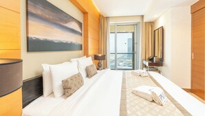 A hotel room with a large bed, a painting on the wall, a desk with a lamp, and a view through the door. - PVH - Emaar Fashion Avenue - 1BR (Dubai)
