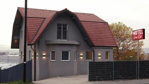A motel with a red-tiled roof, a single-story structure, and a fenced parking area. - Motel Graz Ost  (Graz)