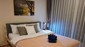 A neatly made bed with a blanket, pillows, and a folded towel on top.