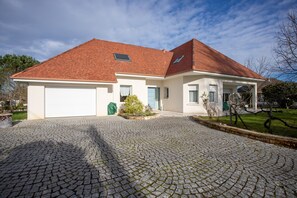 A two-story house with a red-tiled roof, a garage, and a cobblestone driveway.