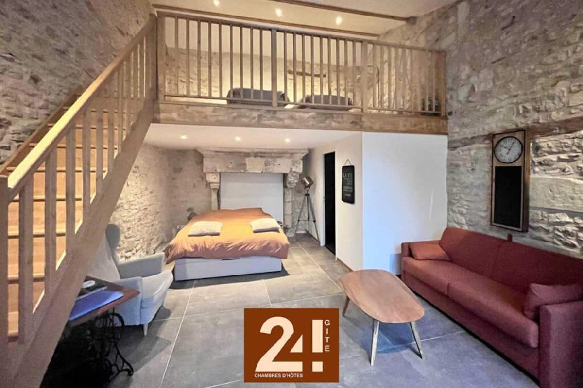 A loft bedroom with a bunk bed, a red sofa, and a wooden staircase.