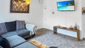 A modern living room with a sofa, a TV, and artwork on the wall.