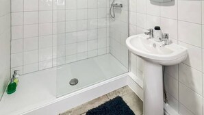 A bathroom with a glass shower enclosure, a white sink, and a mirror.