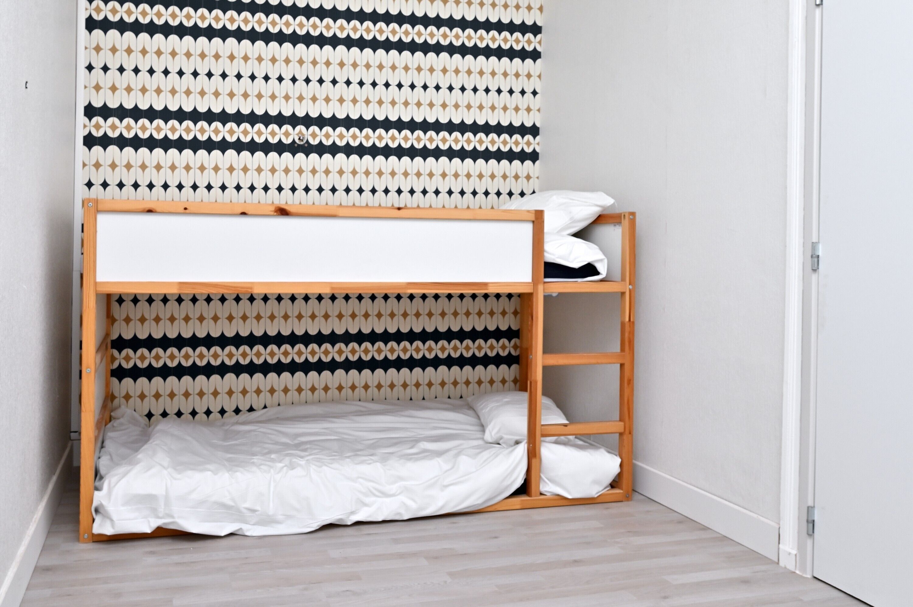 Een stapelbed met een patroon op de muur erachter.