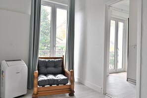 A room with a wooden chair, a Whirlygig air purifier, and a view through a window.