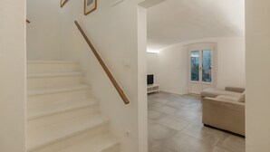 Eine Treppe führt zu einem Wohnbereich mit einer Couch und einem Fernseher.