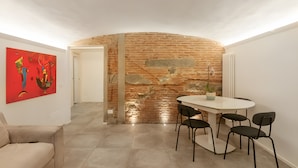 Ein Essbereich mit Backsteinwand, einem weißen Tisch und schwarzen Stühlen.