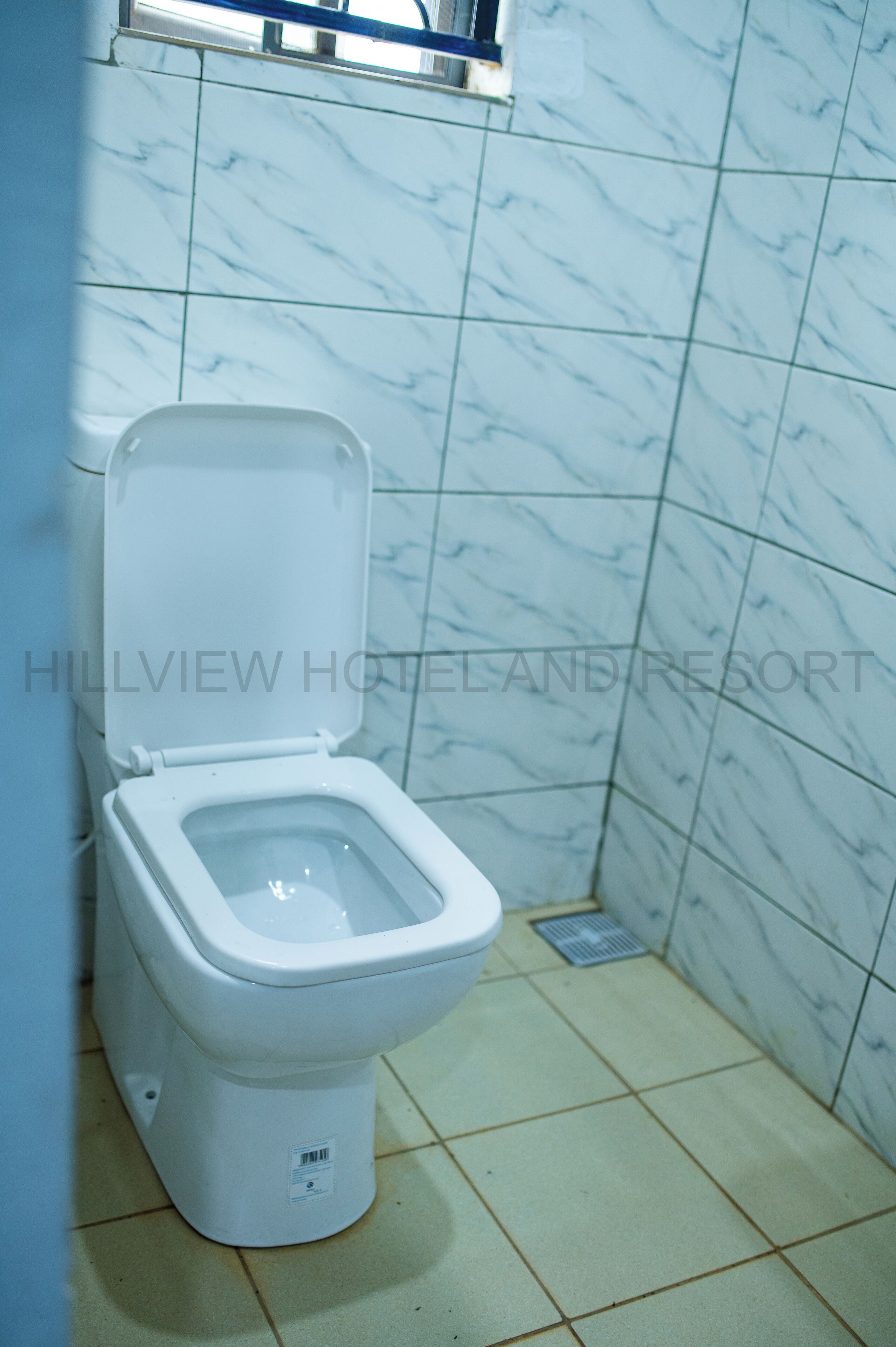 A toilet in a bathroom with a tiled floor and walls.
