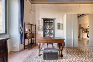 Ein Zimmer mit einem Holztisch, einem Bücherregal, einem Vintage-Radio und einem gemusterten Boden.