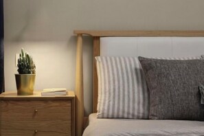 A bed with a wooden headboard, a striped pillow, and a gray pillow. - Vancouver Airport Inn (Richmond)