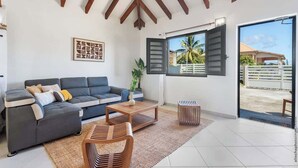 Un salón moderno con un sofá gris, una mesa de centro de madera y vistas al exterior.