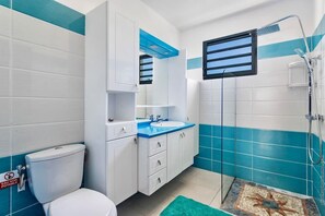 A bathroom with a toilet, sink, and shower area.