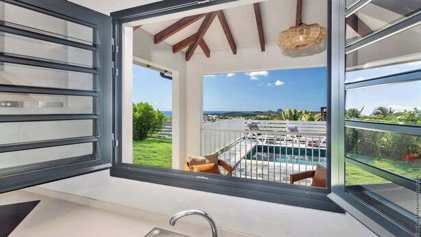 Una cocina moderna con un amplio ventanal que da a una piscina y zona de estar exterior.
