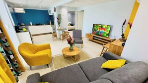 A modern living room with a grey sofa, yellow armchairs, a coffee table, and a TV.