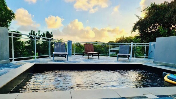 A swimming pool with two lounge chairs and a wooden deck.