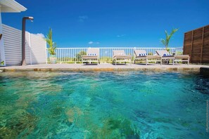 A clear pool with lounge chairs and a white fence. - Villa Tropic Hirondelle - Piscine Vue Mer (Le François)