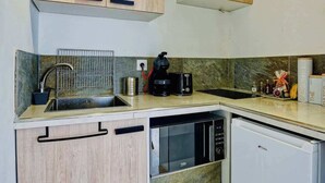 Cozinha compacta com armários de madeira, máquina de lavar louça embutida, micro-ondas e pequena geladeira.