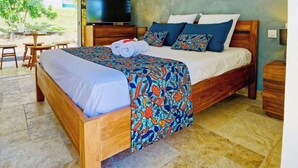 Quarto com cama de madeira, ventilador de teto, televisão e vista para o exterior.