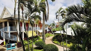 A resort with multiple-story buildings, a central courtyard with palm trees, and a spiral staircase leading to the upper floors. - T2 La Perle - Village Creole (Les Trois-Îlets)