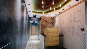 A hallway with a reception desk, a brick wall, and a patterned ceiling. - One Luxury Suites (Belgrade)