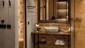 A bathroom with a stone wall, a glass shower enclosure, a white sink, and a mirror. - One Luxury Suites (Belgrade)