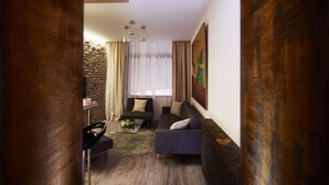 A modern living room with a sofa, a coffee table, and a dining area with a table and chairs. - One Luxury Suites (Belgrade)